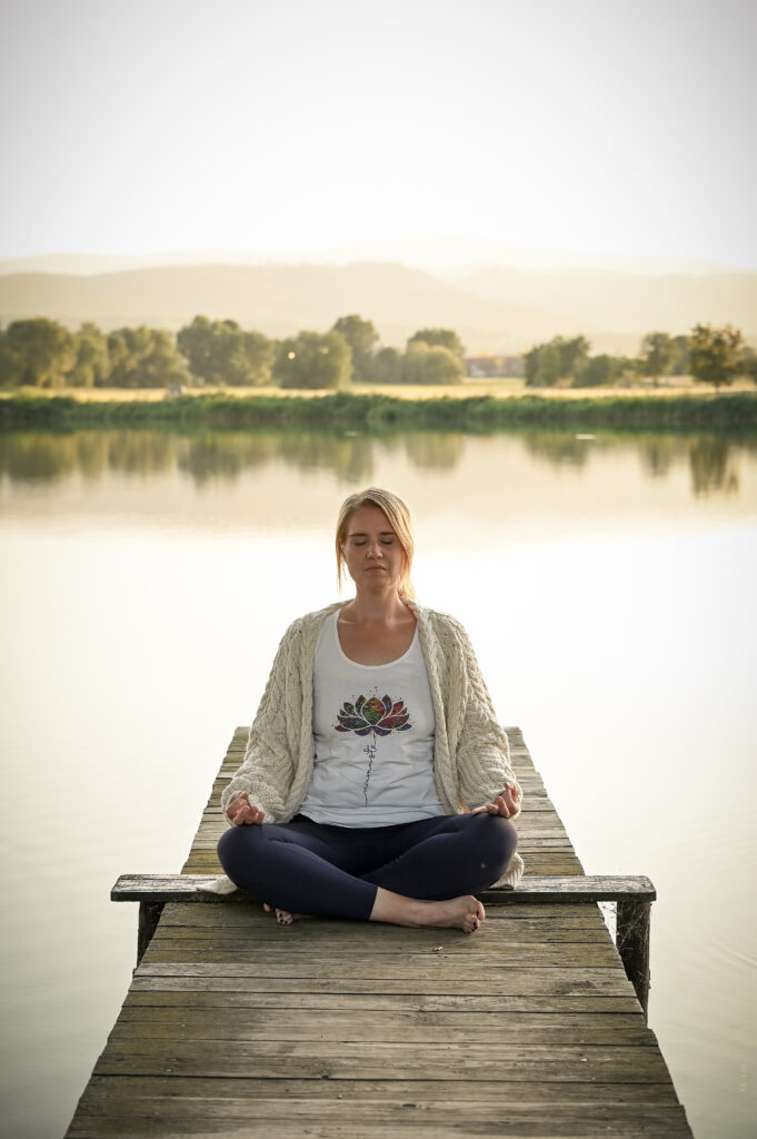 Yogalehrerin Anna Miehe, meditiert im Schneidersitz auf einem Steg